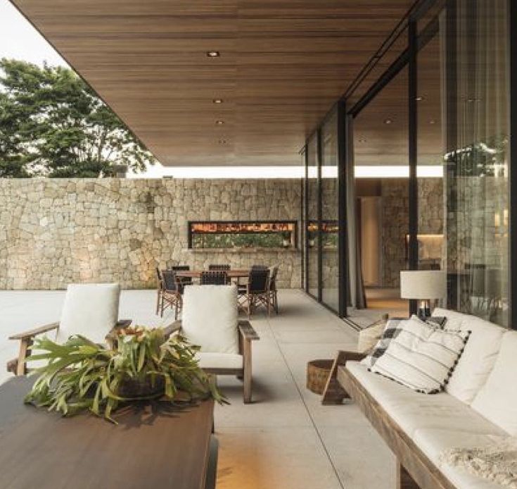 Varanda gourmet com lareira embutida em parede de pedra e cobertura em madeira, construção alto padrão