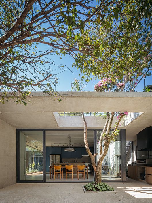 Fachada de residência de alto padrão com laje de concreto aparente e pátio interno arborizado