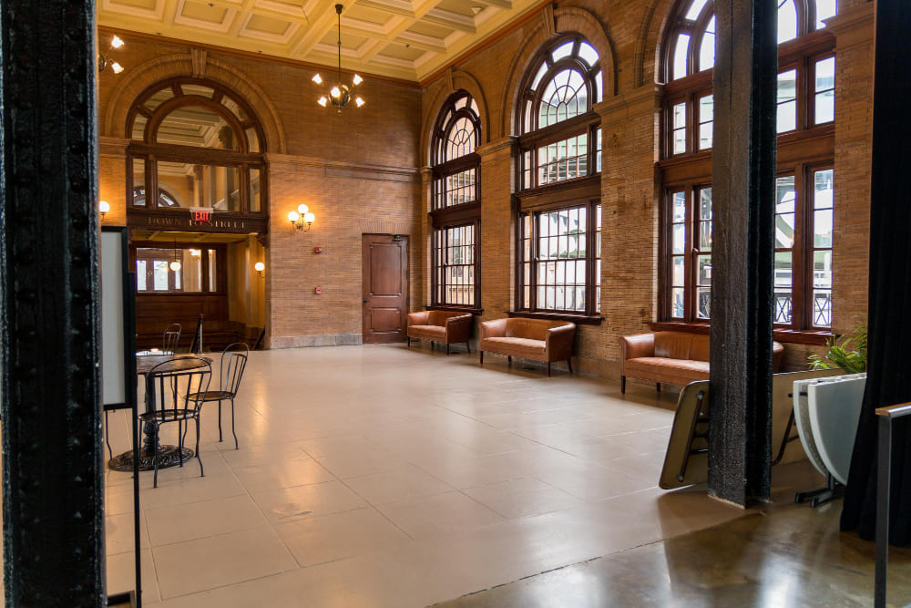 Lobby corporativo em edifício histórico retrofitado, com janelas em arco e tijolo aparente, reforma comercial de alto padrão