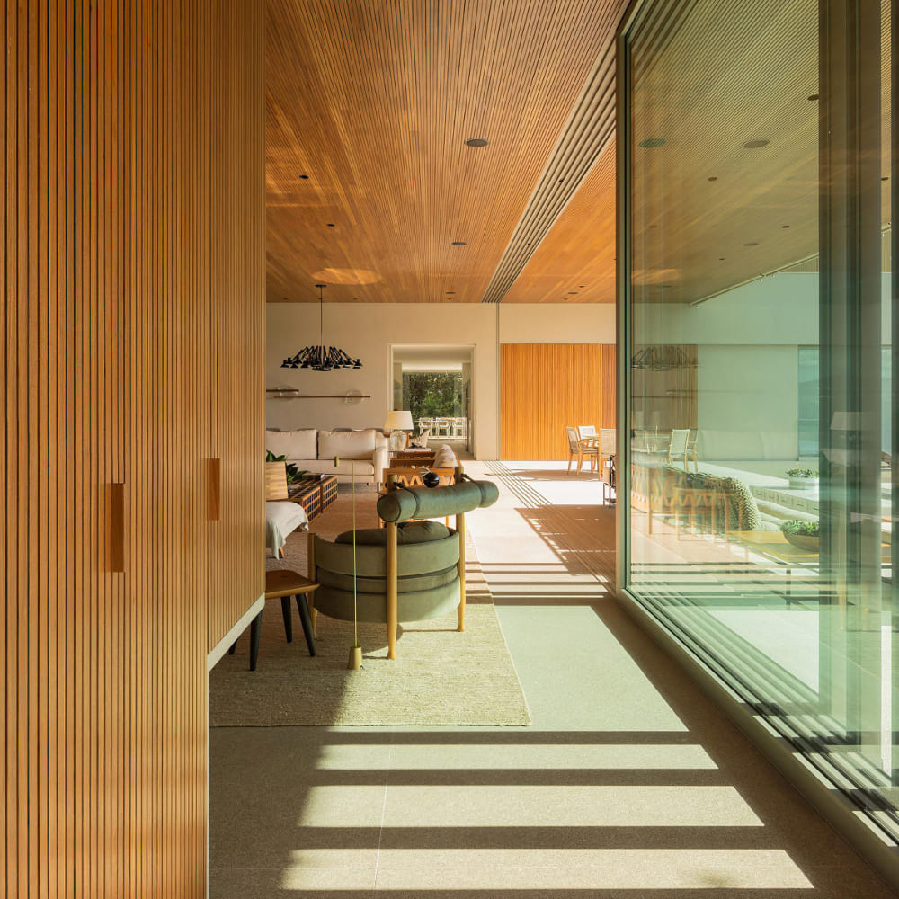 Sala de estar com teto ripado em madeira integrando ambiente interno e área externa, construção residencial de alto padrão