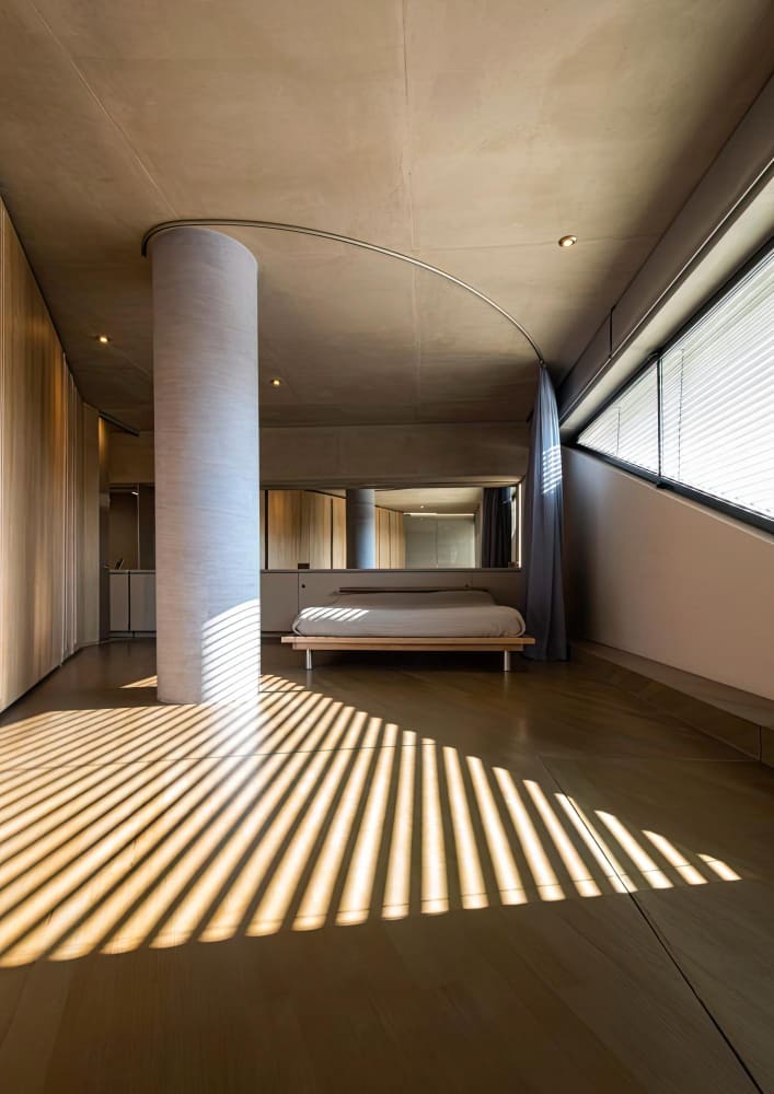 Suíte com pé-direito em concreto aparente e luz natural marcante, reforma residencial de alto padrão
